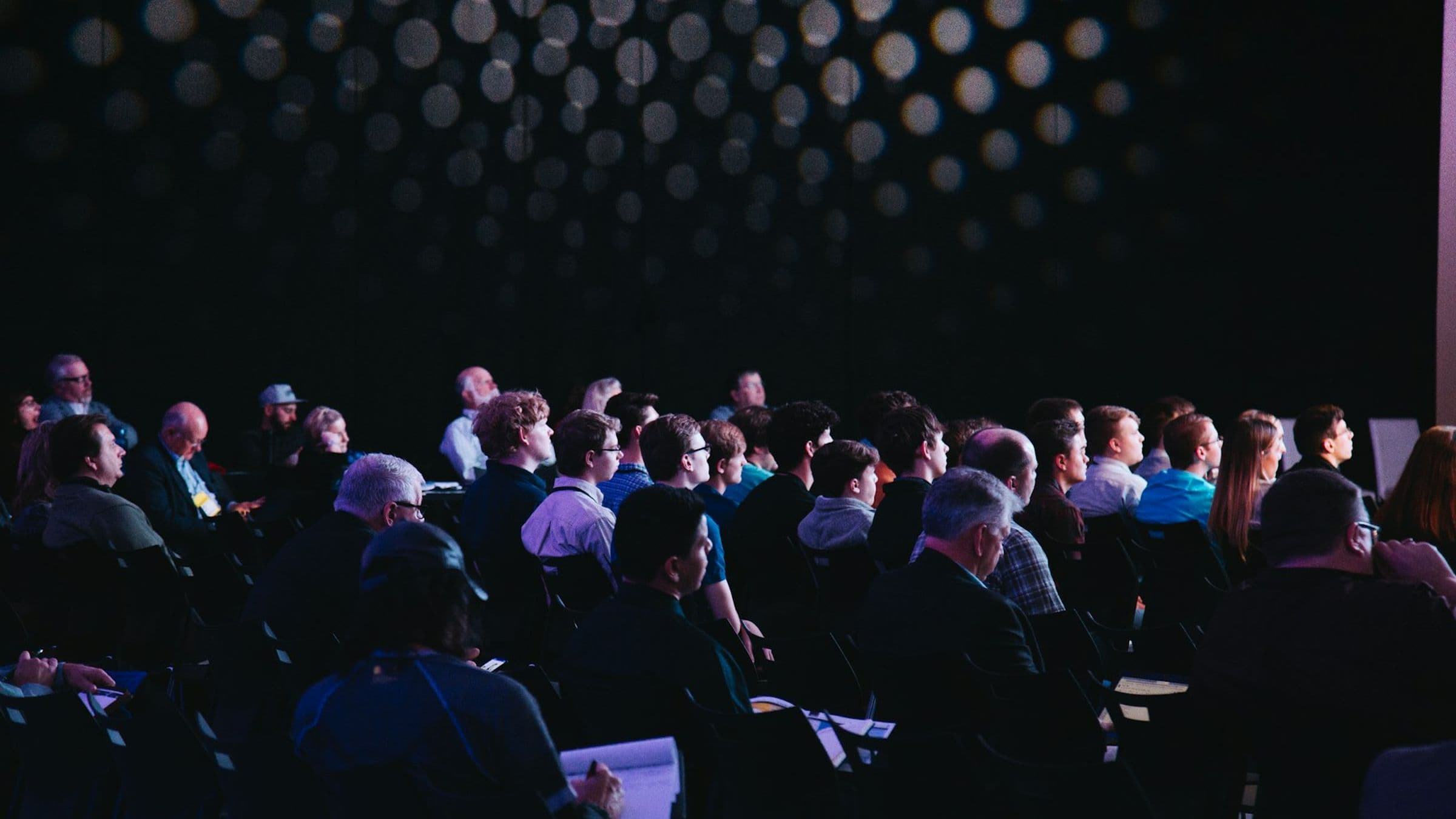 Vue d'une salle de conférence pendant une session, public assis face à la scène.